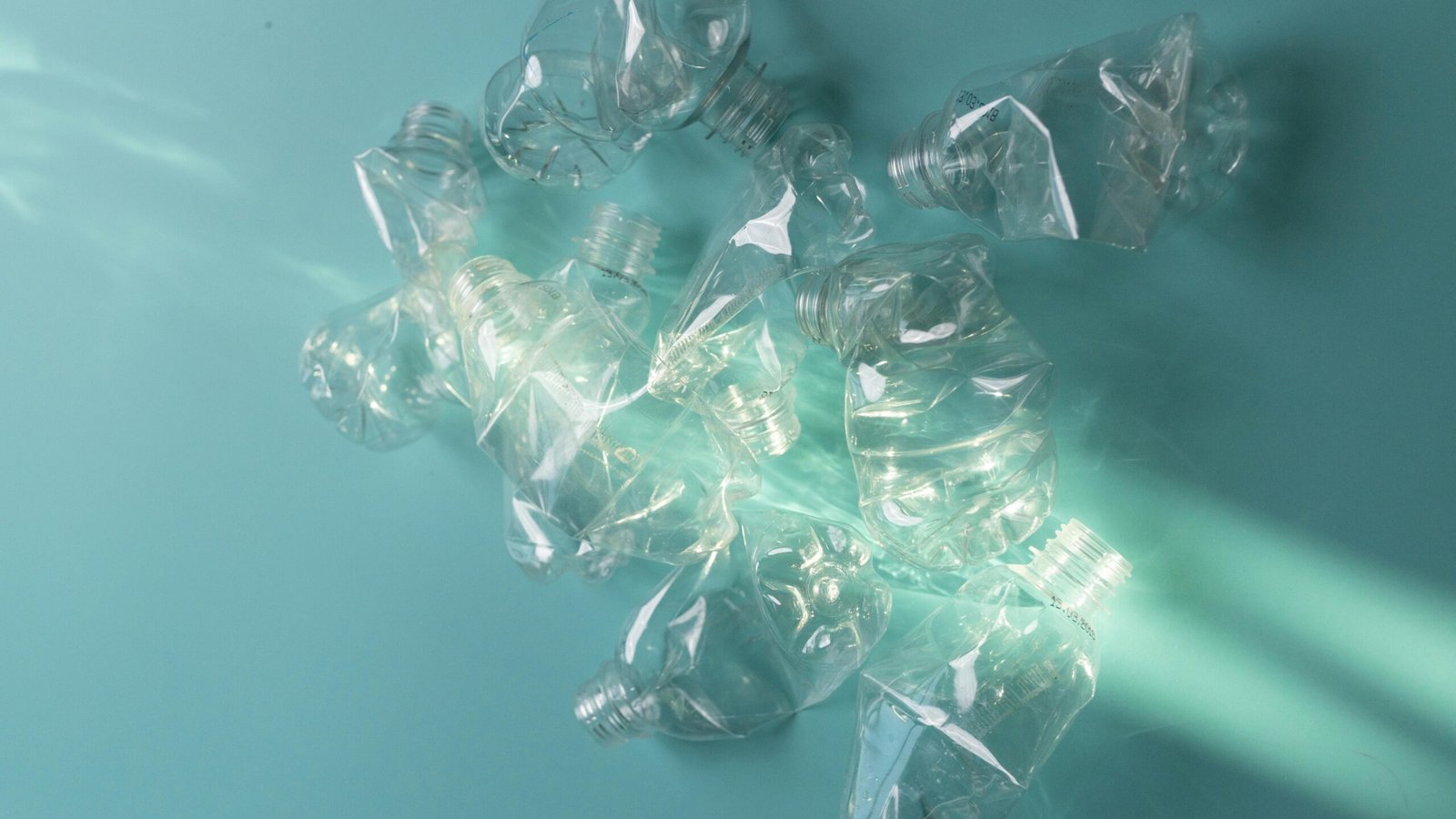 Crushed plastic bottles creatively arranged in studio lighting for recycling.