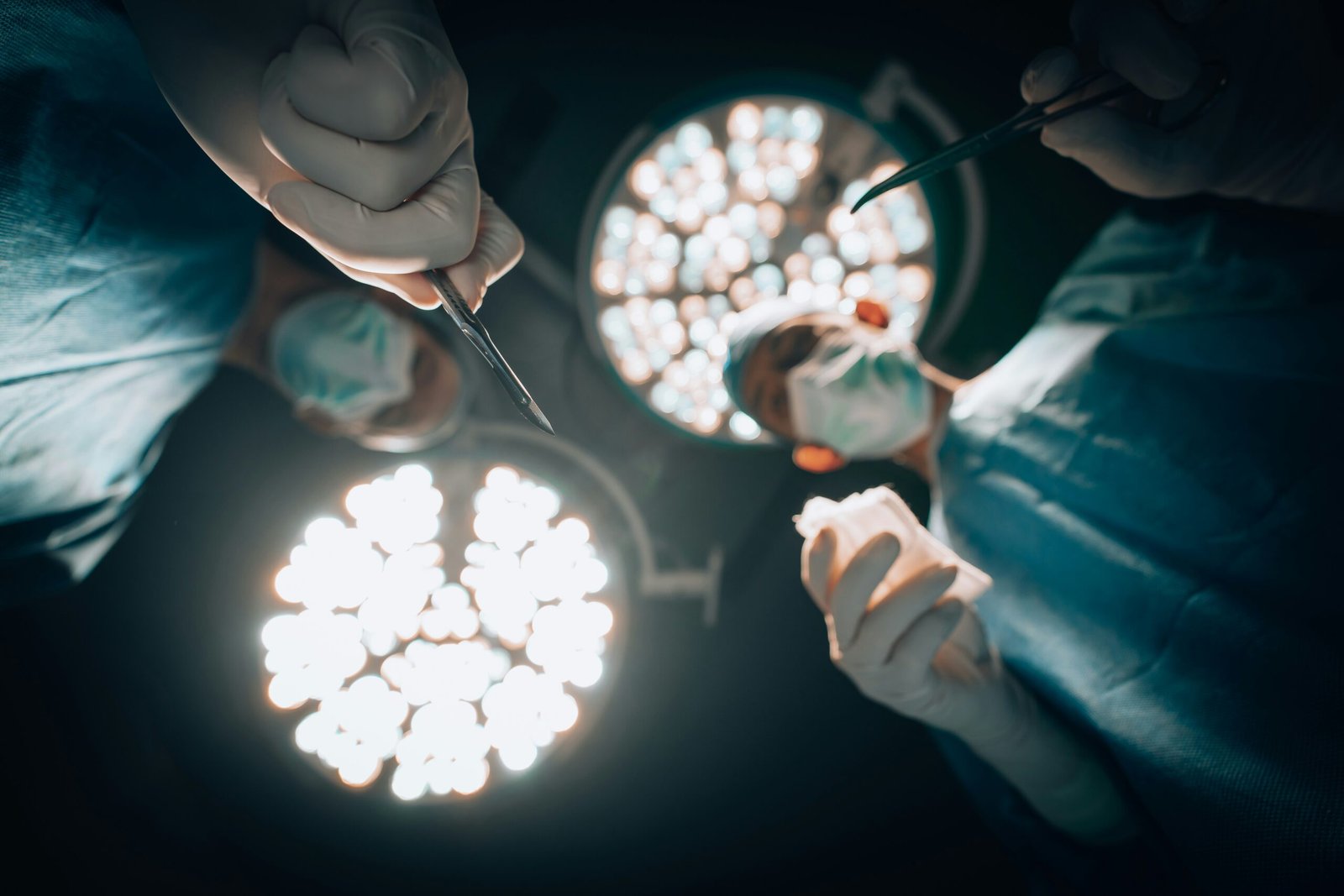 Surgical Team Unity: Illuminating the Path to Healing - Step into the world of surgical excellence as a dedicated team of medics collaborates in the operating room. In this image, amidst the darkness, the focused lights shine upon the patient lying on the bed. Witness the unity and expertise of these healthcare professionals as they work together to navigate the path towards healing.