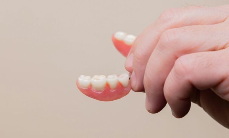 man holds his denture.