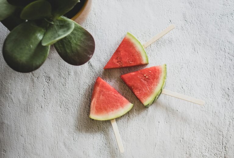 Three vibrant watermelon slices on popsicle sticks, perfect for a summer treat.