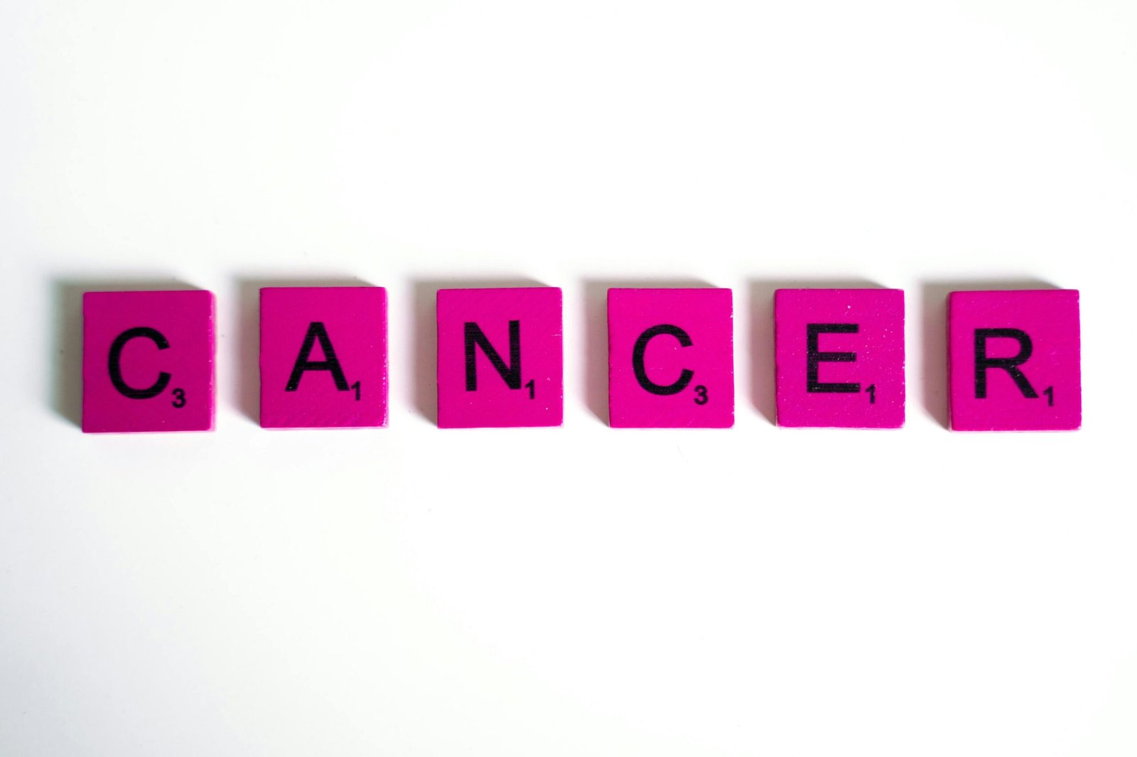 Word 'cancer' spelled with pink letter tiles.