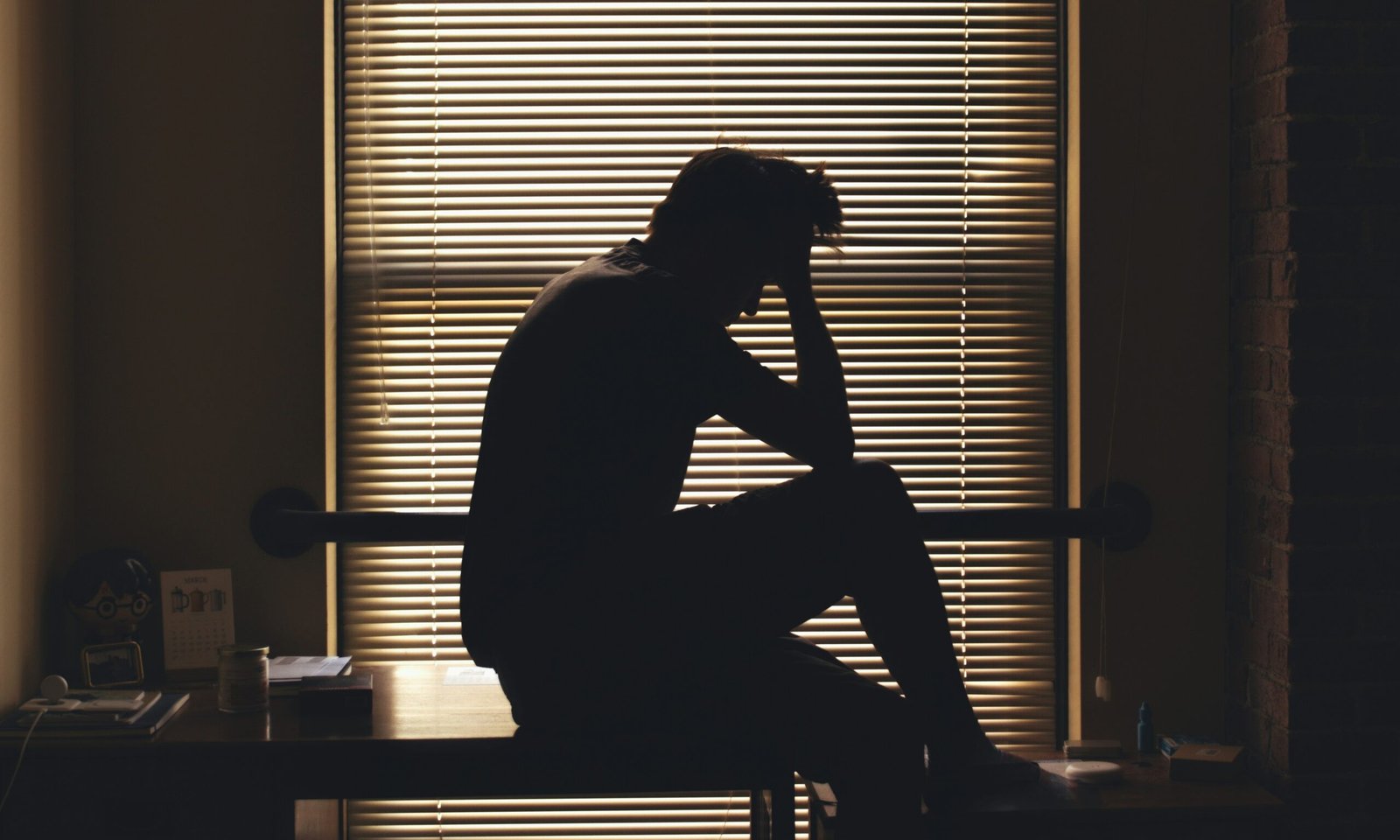 A man sitting in front of window blinds