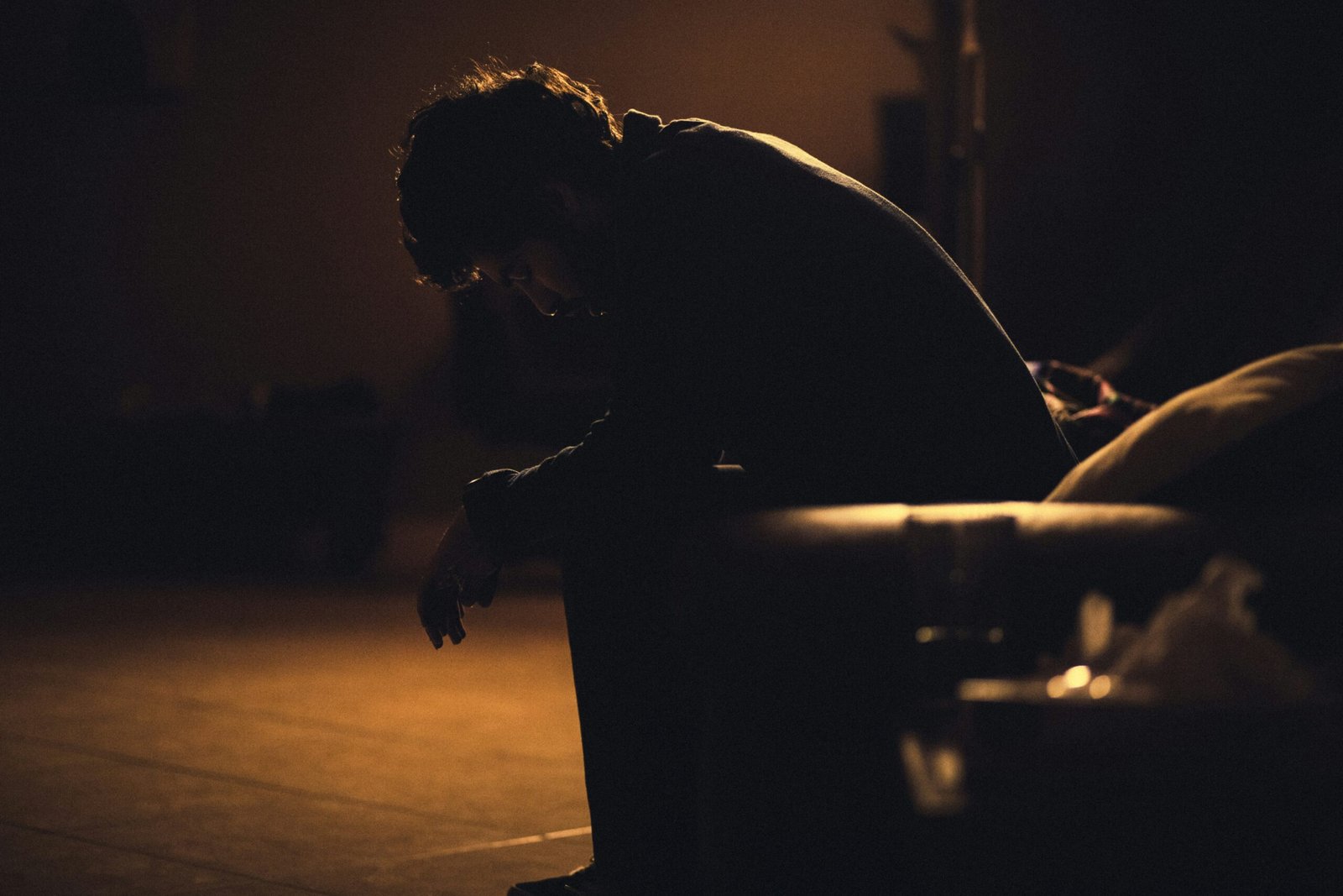 Men sitting on chair in dark room.